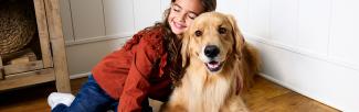 A girl hugging a dog while sitting on the floor