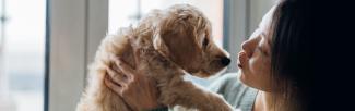 woman kissing puppy on nose